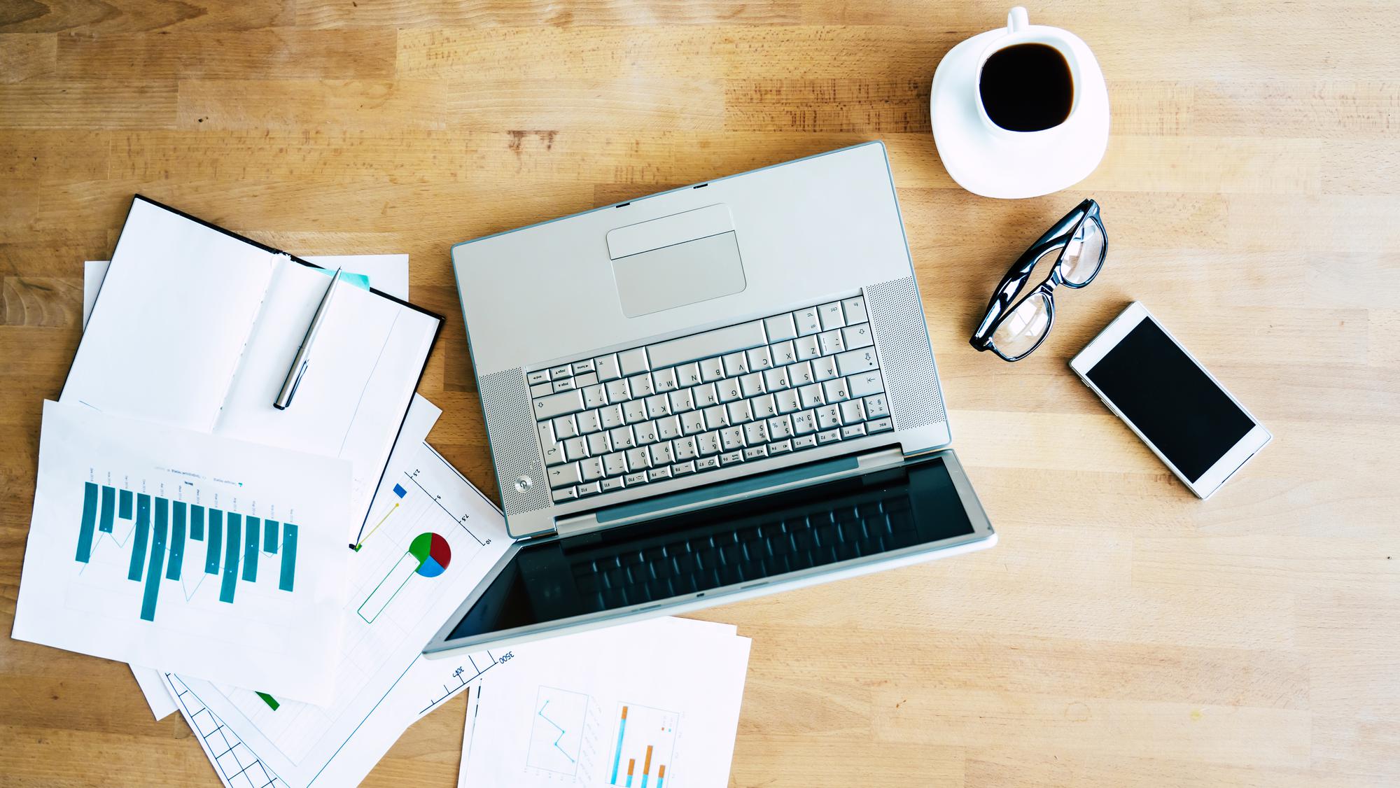 Office workspace with financial reports and laptop